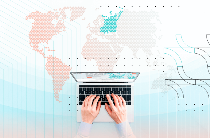A person working on a laptop with a world map in front of them.