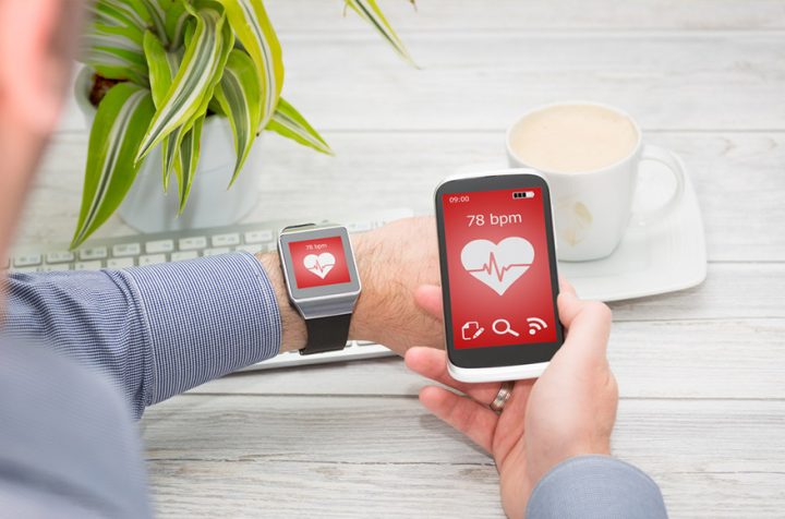Man checking his pulse on a smartwatch and smartphone.
