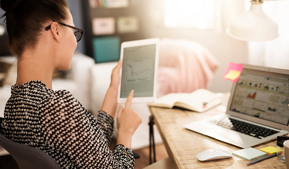 Girl holding tablet and using laptop at modern office