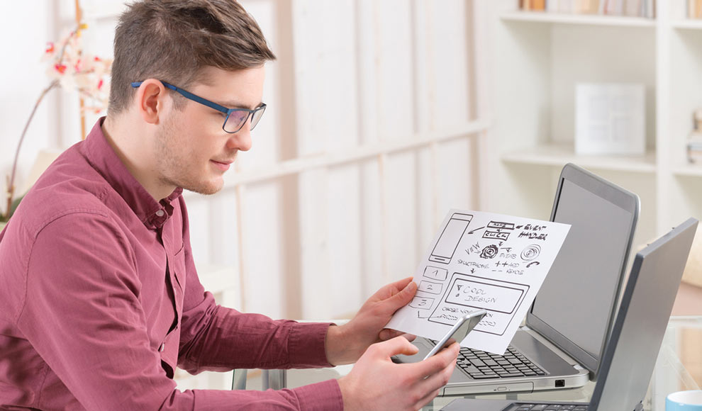 Man Working With Diagram And Using Smartphone