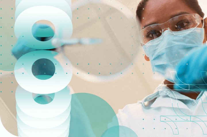 Medical professional wearing a mask and goggles, holding a syringe.