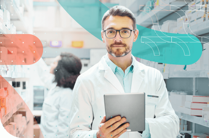Pharmacist holding a tablet while standing in a pharmacy full of medications.