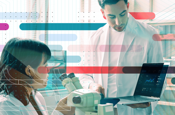 Two scientists collaborating with a laptop and microscope.