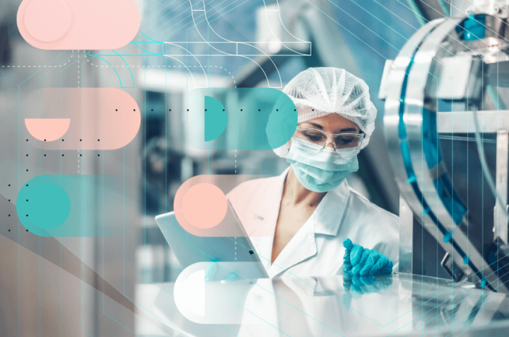 Scientist in a cleanroom wearing protective clothing, using a tablet to monitor processes.